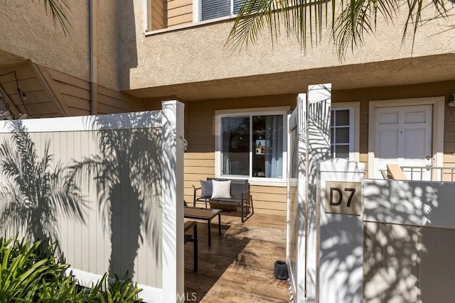 entrance to property with fence and stucco siding