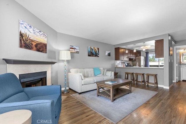 living room with baseboards, dark wood finished floors, and a tiled fireplace