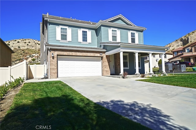 view of front of home featuring brick siding, concrete driveway, a front yard, fence, and a garage