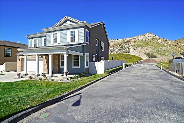 traditional-style house with a garage, concrete driveway, fence, and a mountain view