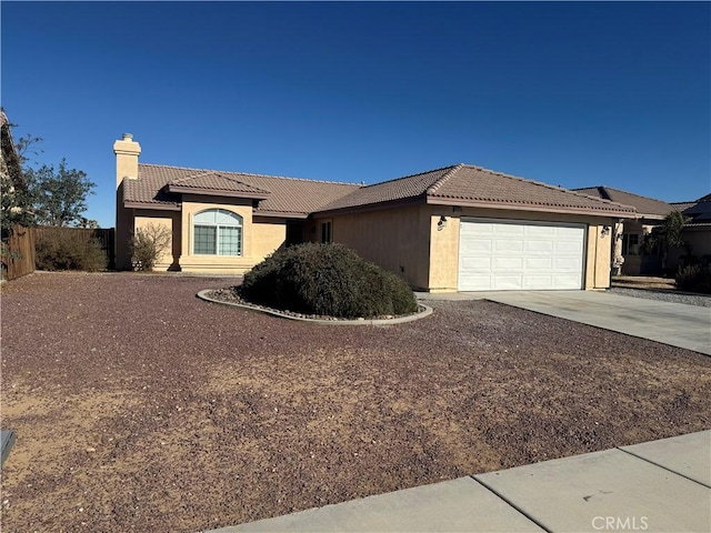 view of front of house featuring driveway, a tile roof, a chimney, an attached garage, and fence