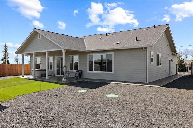 back of house featuring a shingled roof, fence, and a patio