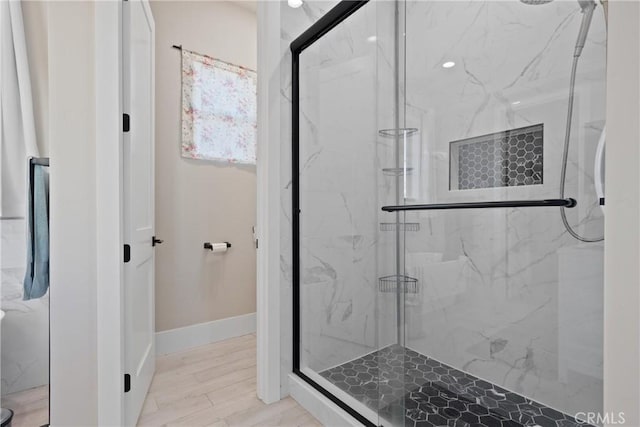 full bathroom featuring a marble finish shower, baseboards, and wood finished floors