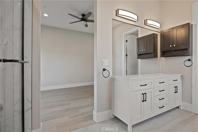 full bathroom featuring a ceiling fan, vanity, baseboards, and wood finished floors