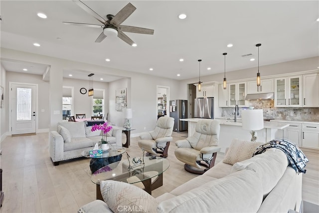 living area featuring baseboards, light wood-type flooring, visible vents, and recessed lighting