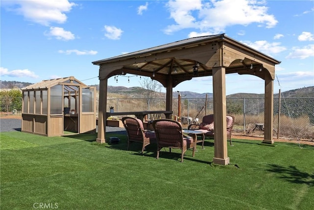 view of home's community featuring an outbuilding, an exterior structure, a lawn, fence, and a mountain view