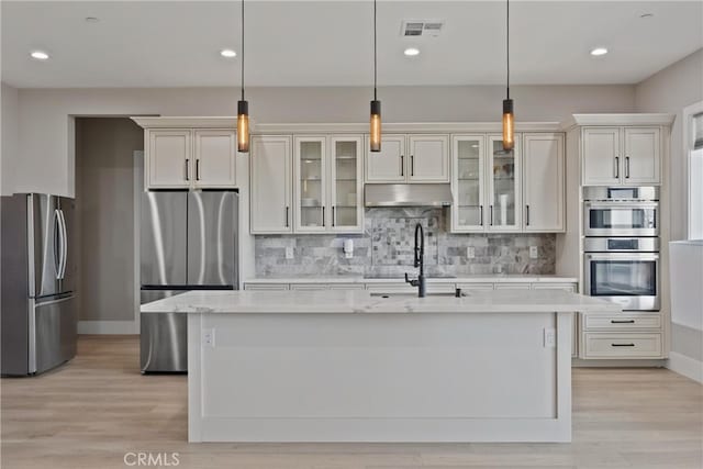 kitchen with under cabinet range hood, a sink, visible vents, appliances with stainless steel finishes, and tasteful backsplash