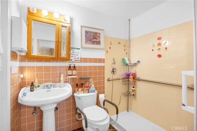 bathroom featuring a wainscoted wall, tiled shower, toilet, and tile walls