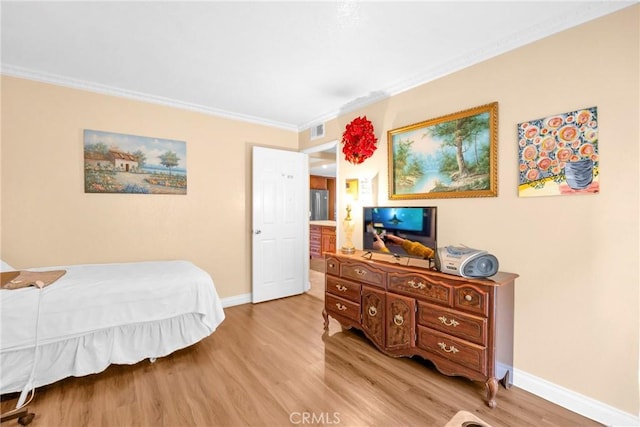 bedroom with light wood-style flooring, visible vents, baseboards, and ornamental molding