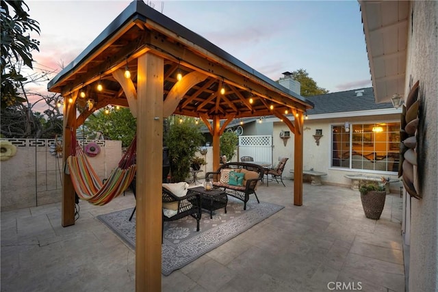 patio terrace at dusk featuring fence, an outdoor living space, and a gazebo