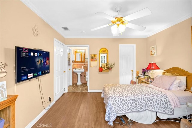 bedroom featuring ornamental molding, visible vents, baseboards, and wood finished floors