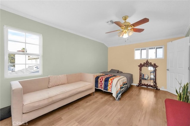 bedroom featuring light wood-type flooring, visible vents, ornamental molding, and a ceiling fan