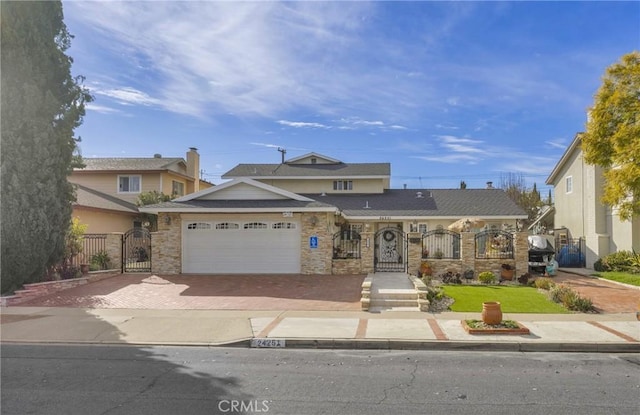 view of front of house featuring a fenced front yard, an attached garage, stone siding, decorative driveway, and a gate