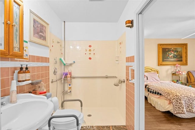 bathroom featuring tile walls, toilet, ensuite bathroom, a shower stall, and a sink