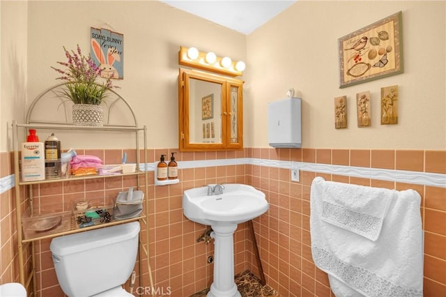 bathroom featuring wainscoting, toilet, and tile walls