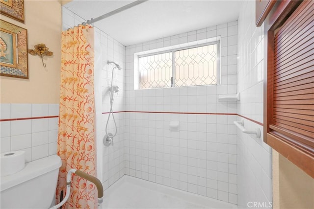 bathroom with a tile shower, toilet, and tile walls