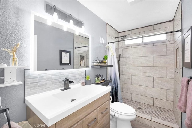 bathroom with vanity, a stall shower, backsplash, and toilet