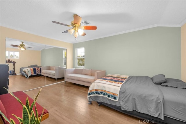 bedroom with vaulted ceiling, ornamental molding, multiple windows, and wood finished floors