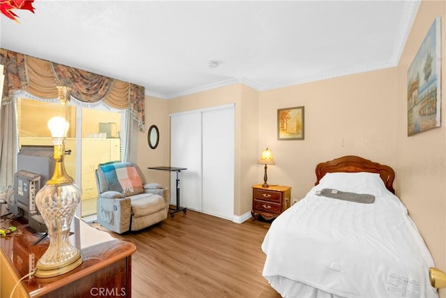 bedroom featuring access to exterior, a closet, wood finished floors, and crown molding