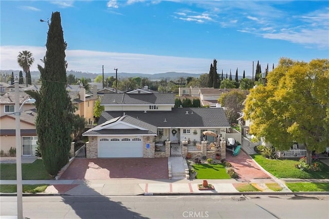 view of front of house featuring a fenced front yard, a residential view, decorative driveway, and a garage