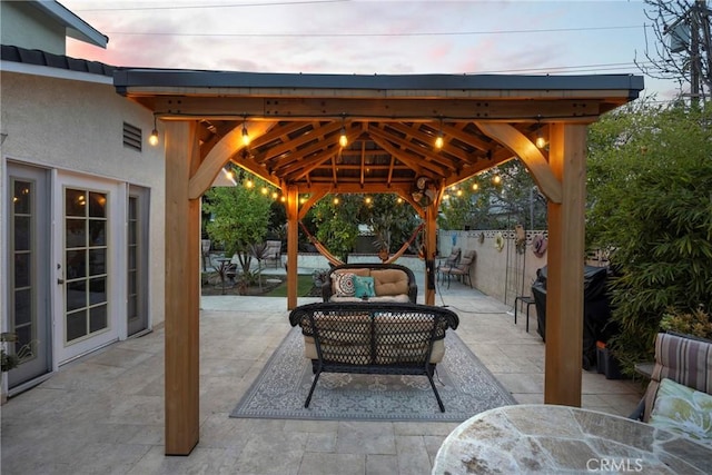 patio terrace at dusk with a gazebo, outdoor dining space, outdoor lounge area, and fence