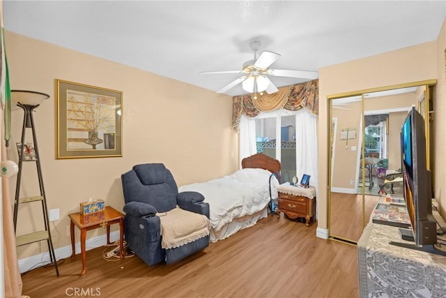 bedroom featuring a closet, multiple windows, baseboards, and wood finished floors