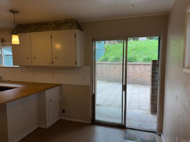 kitchen featuring hanging light fixtures, white cabinets, and concrete floors