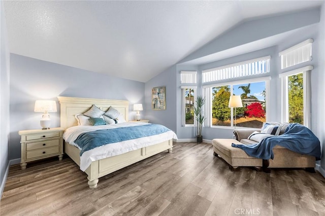 bedroom with lofted ceiling, wood finished floors, and baseboards