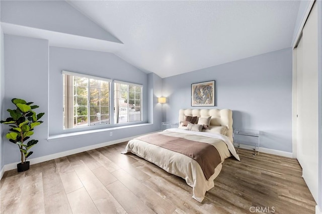 bedroom with lofted ceiling, baseboards, and wood finished floors