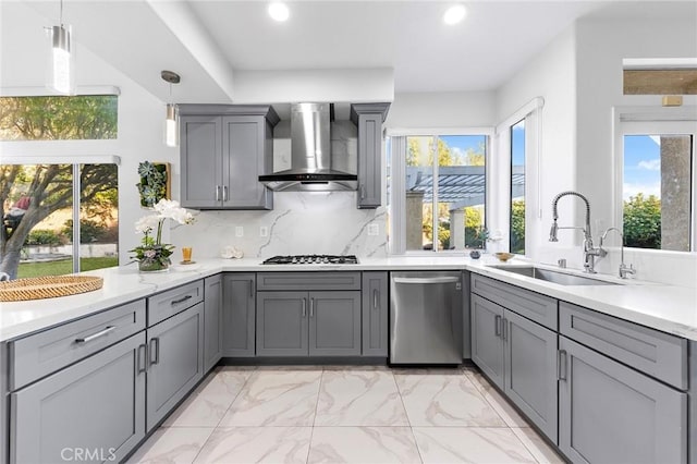 kitchen with decorative backsplash, wall chimney exhaust hood, gray cabinets, stainless steel dishwasher, and a sink