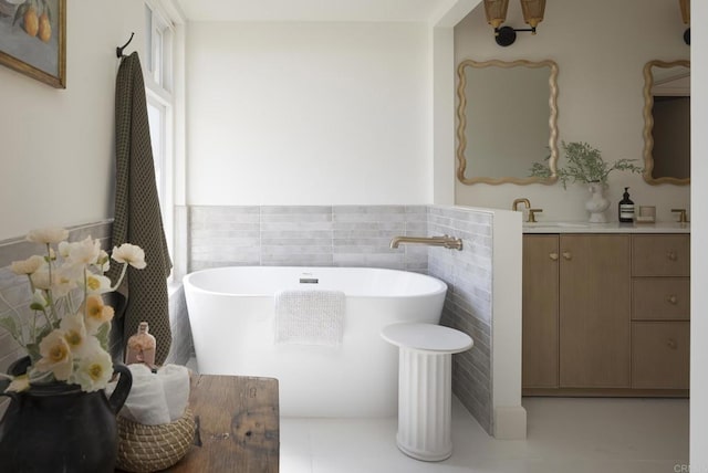 full bathroom featuring wainscoting, a freestanding bath, tile walls, and vanity