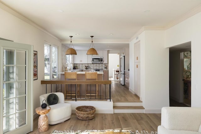 kitchen featuring light wood-style flooring, a peninsula, light countertops, crown molding, and backsplash