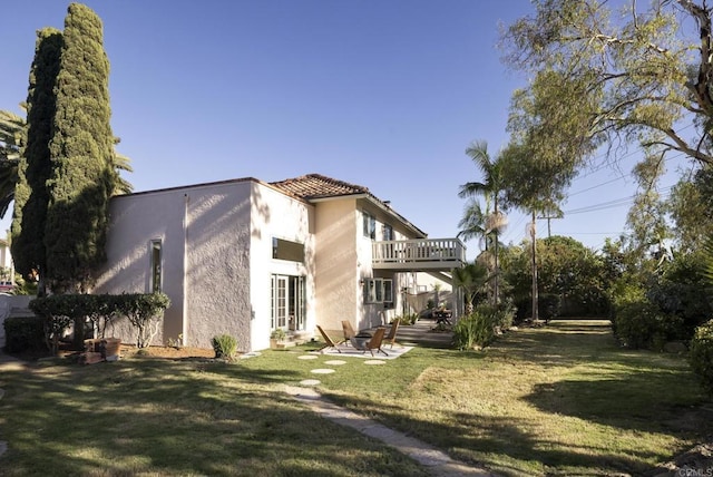 exterior space with a yard, a balcony, and stucco siding