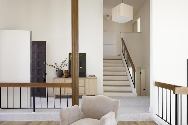 staircase featuring wood finished floors and a towering ceiling