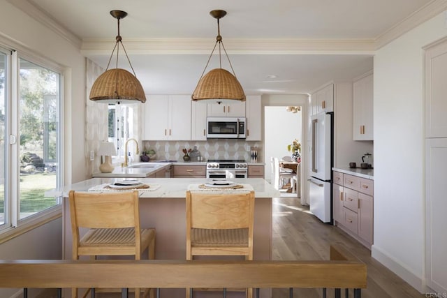 kitchen with high end appliances, light countertops, dark wood-type flooring, plenty of natural light, and a peninsula