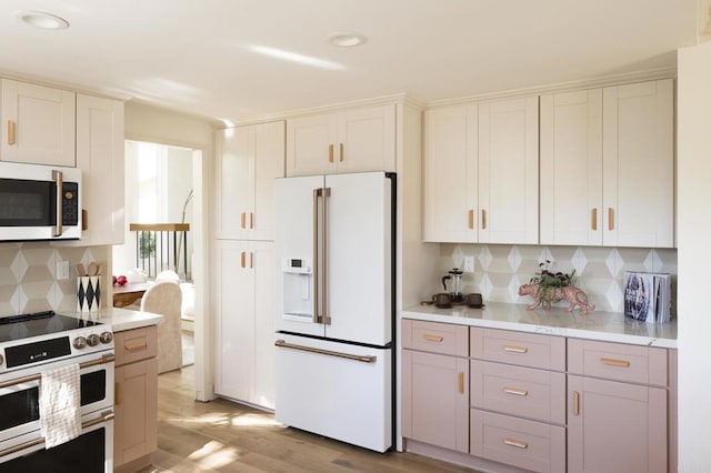 kitchen featuring white appliances, tasteful backsplash, light countertops, light wood-type flooring, and white cabinetry