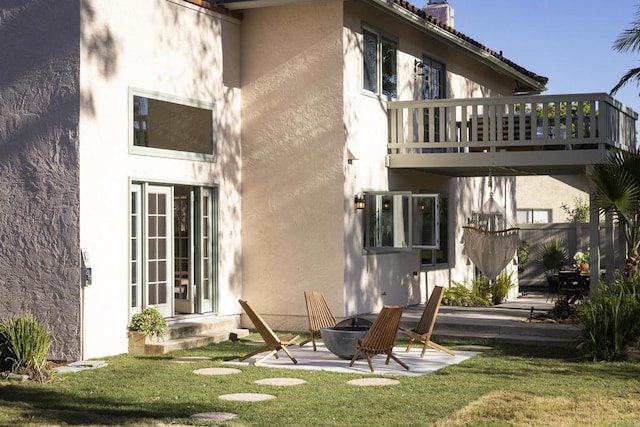 back of house featuring a yard, stucco siding, a patio area, fence, and a balcony