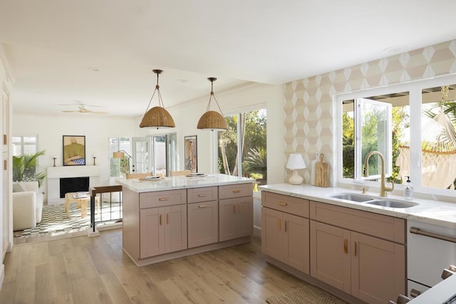 kitchen with decorative light fixtures, a fireplace, a sink, and light wood-style flooring