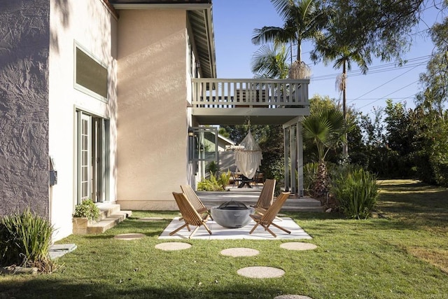 view of yard with entry steps, an outdoor fire pit, a patio area, and a balcony