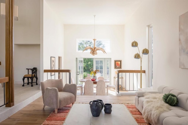 living area featuring a high ceiling, a chandelier, and wood finished floors