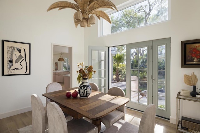 dining room featuring baseboards, a high ceiling, and light wood-style floors