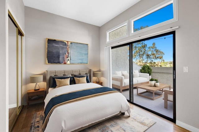 bedroom featuring access to exterior, baseboards, and wood finished floors