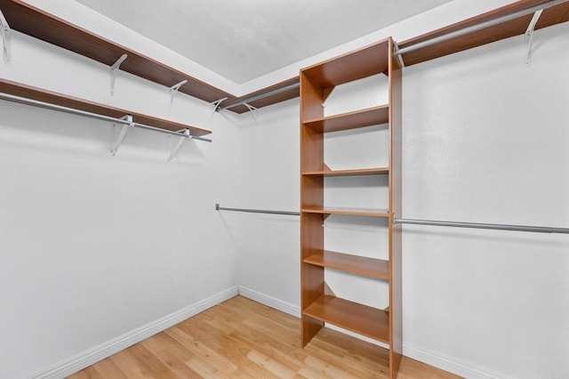 walk in closet with light wood-style floors