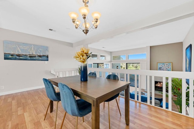 dining area featuring light wood-style floors, a chandelier, visible vents, and baseboards