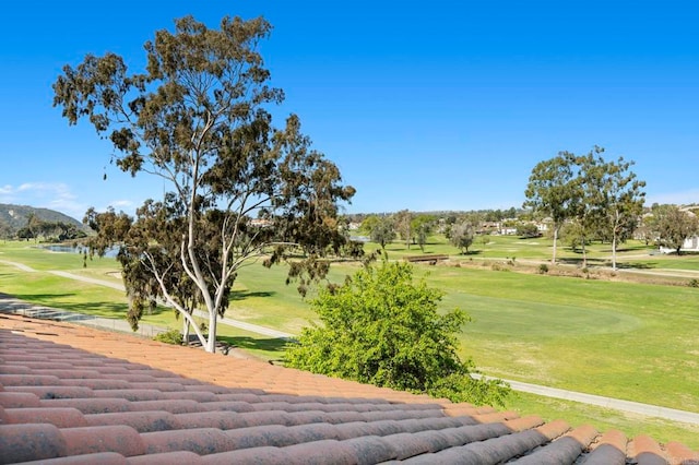 view of home's community featuring view of golf course and a yard