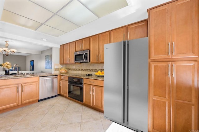 kitchen featuring light tile patterned floors, light stone countertops, a sink, decorative backsplash, and black appliances