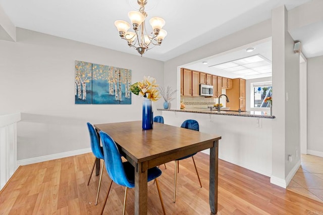 dining area with light wood-style floors, baseboards, and a chandelier