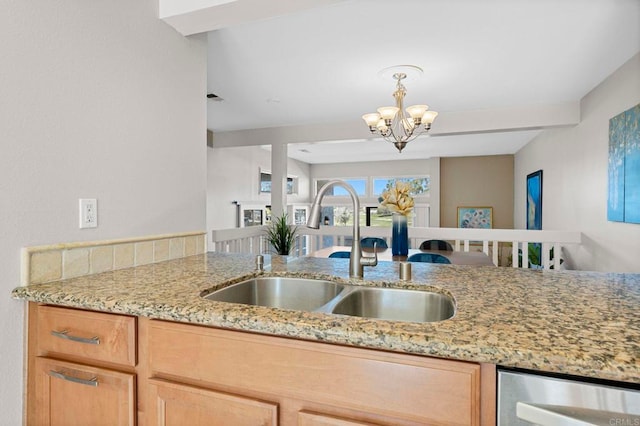 kitchen featuring light stone counters, wine cooler, pendant lighting, a sink, and a chandelier