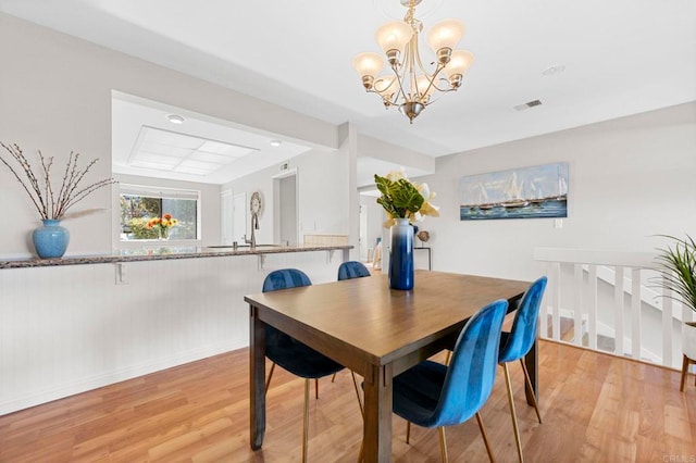 dining space featuring light wood finished floors, visible vents, and a chandelier