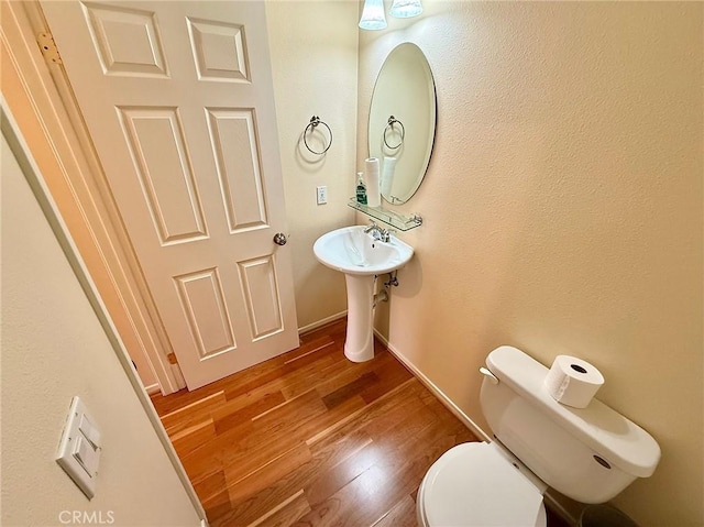 bathroom featuring baseboards, toilet, and wood finished floors